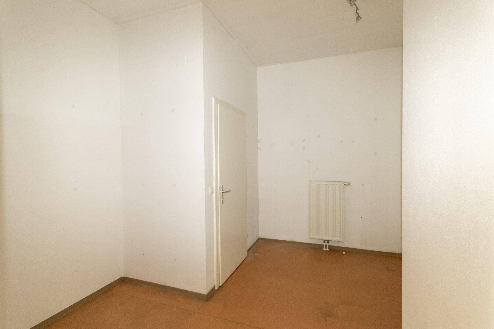 Kleiner, heller Raum mit Tür und Heizkörper, vielseitig nutzbar als Abstellraum.