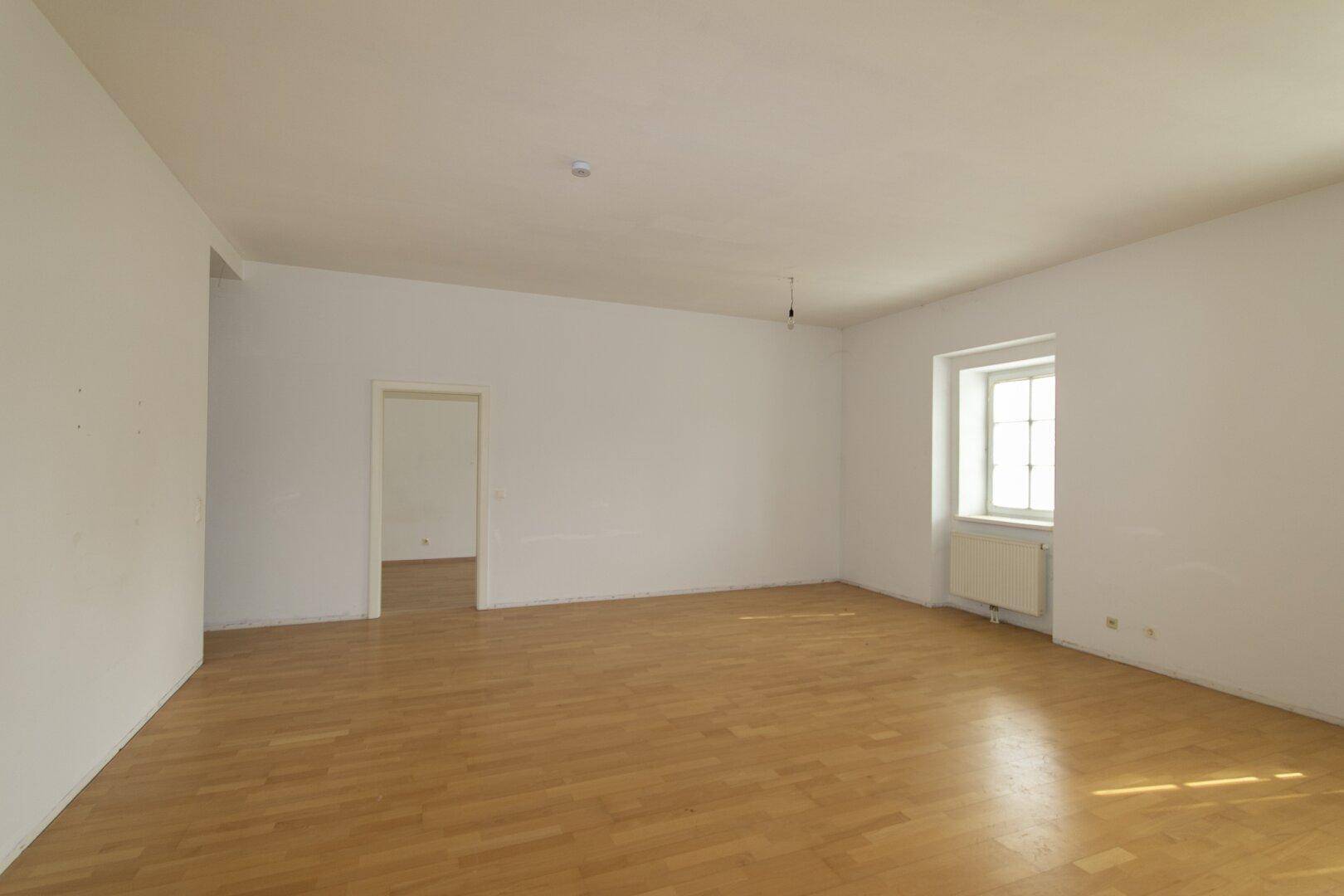Heller, leerer Raum mit Parkettboden und einem Fenster, bietet viel Potenzial für die Einrichtung.