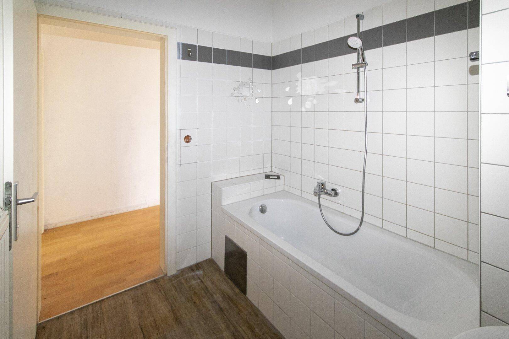 Modern gefliestes Badezimmer mit Badewanne und Duschfunktion, bietet Komfort und Funktionalität.