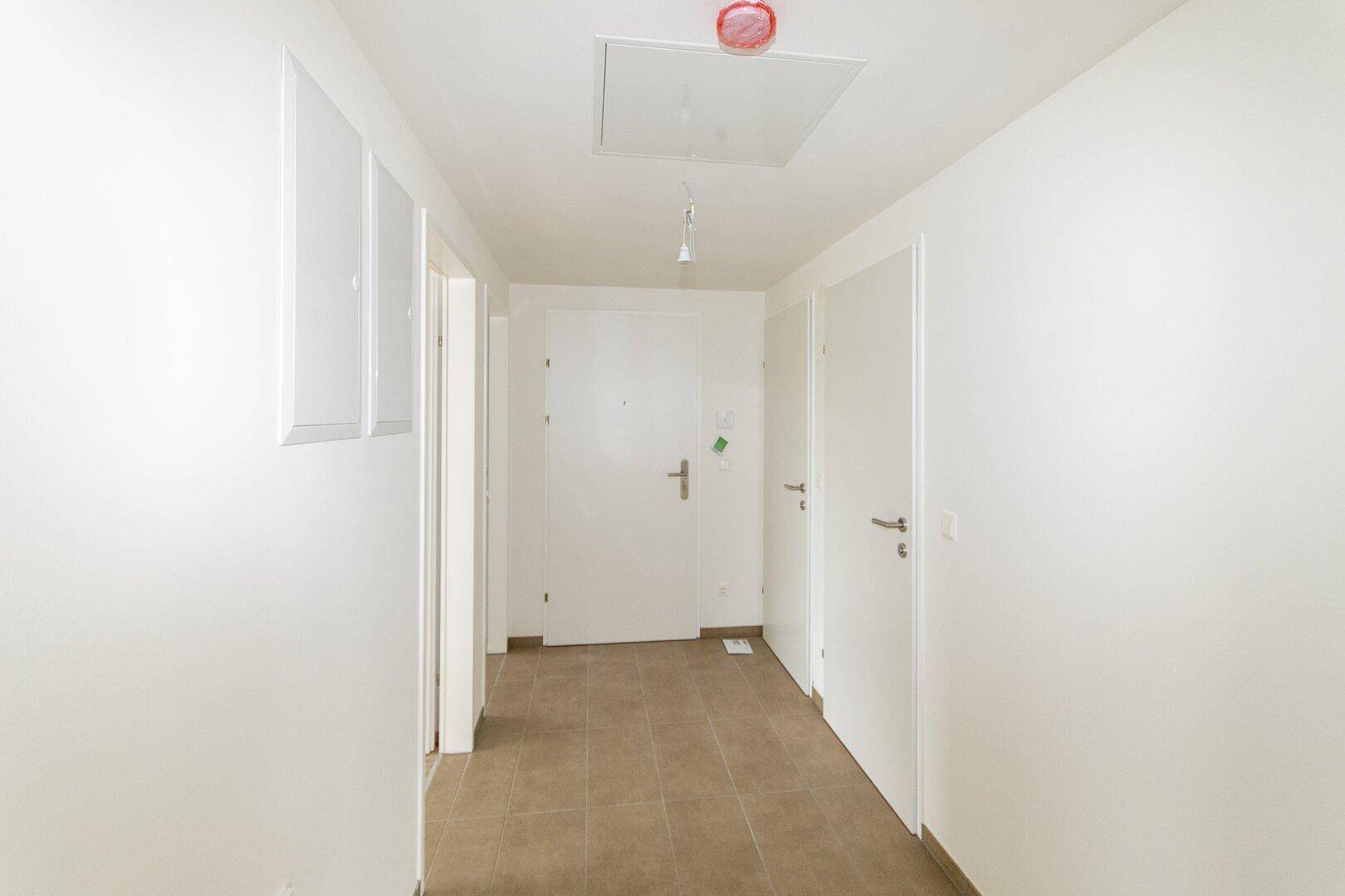 Heller Flur mit Fliesenboden und mehreren Türen, führt zu den verschiedenen Räumen.