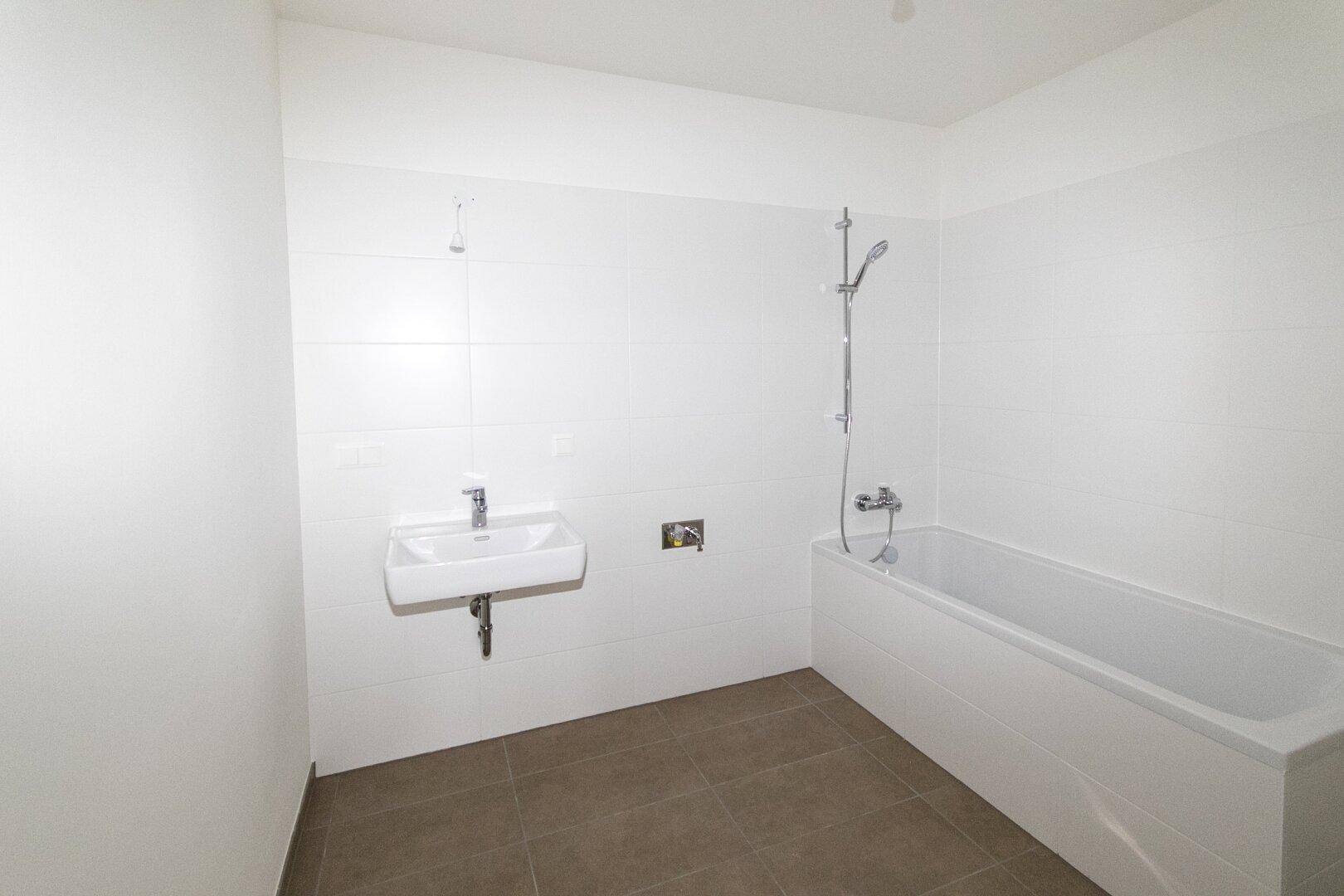 Modernes Badezimmer mit Badewanne und Waschbecken, hell gefliest und funktional.