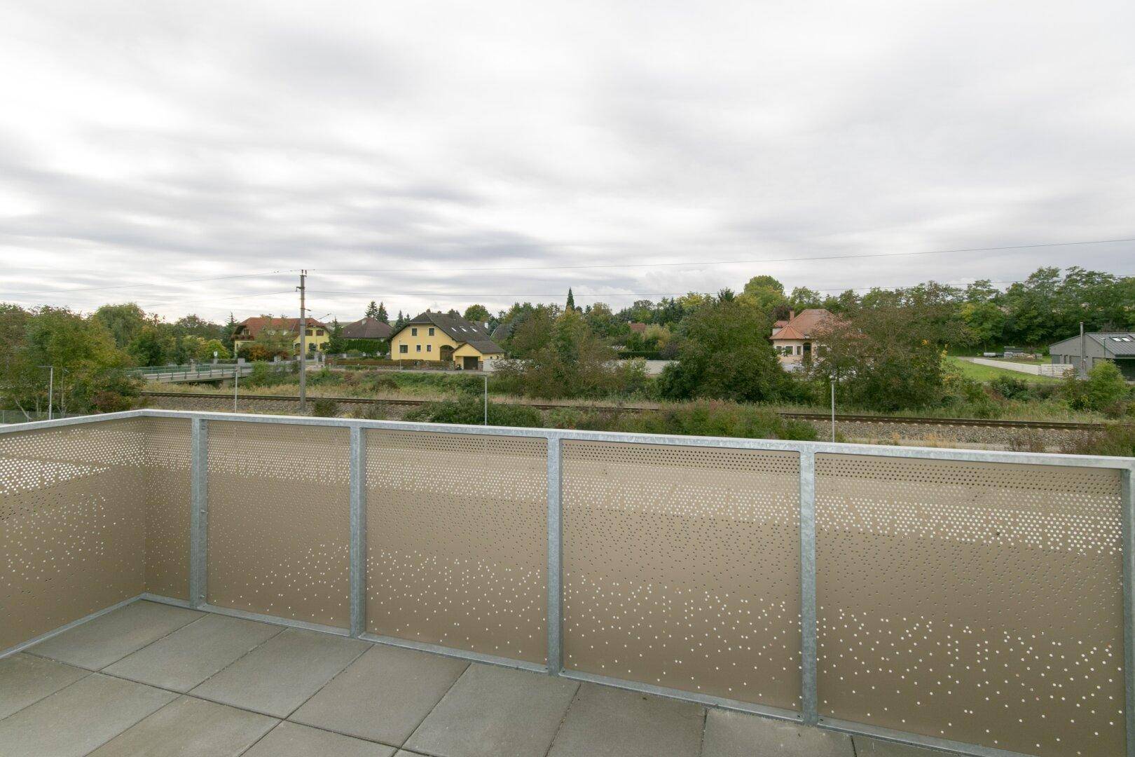 Geräumiger Balkon mit Blick auf die ländliche Umgebung und angrenzende Wohnhäuser.