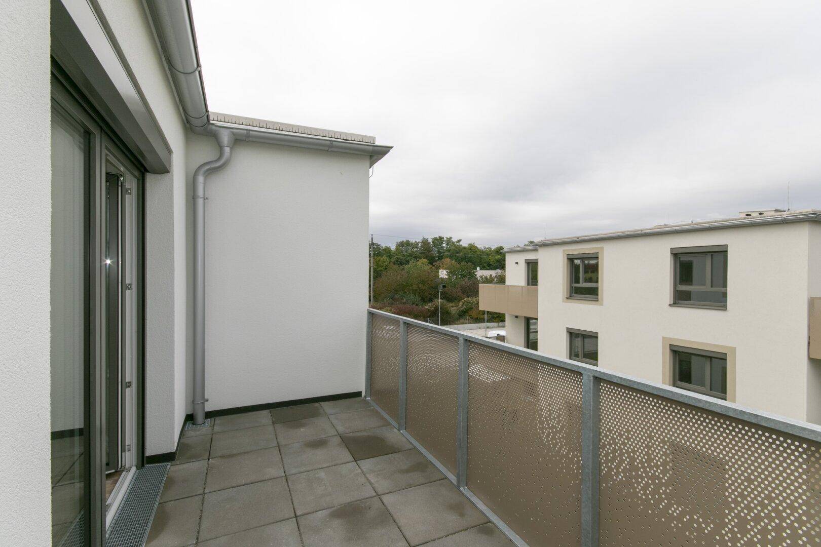 Heller Balkon mit Fliesenboden und moderner Metallbrüstung, ideal für entspannte Stunden.