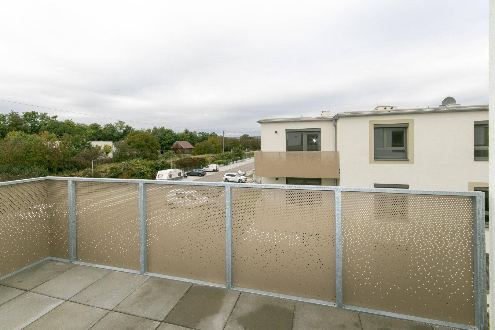 Geräumiger Balkon mit Fliesenboden und moderner Lochblechbrüstung, mit Blick auf die Umgebung.