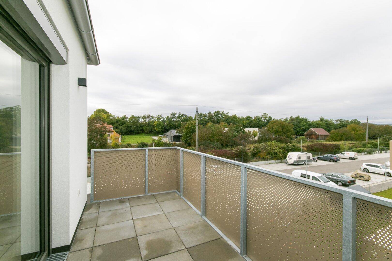 Heller Balkon mit Fliesen und moderner Brüstung, bietet einen Ausblick auf die umliegende Bebauung.