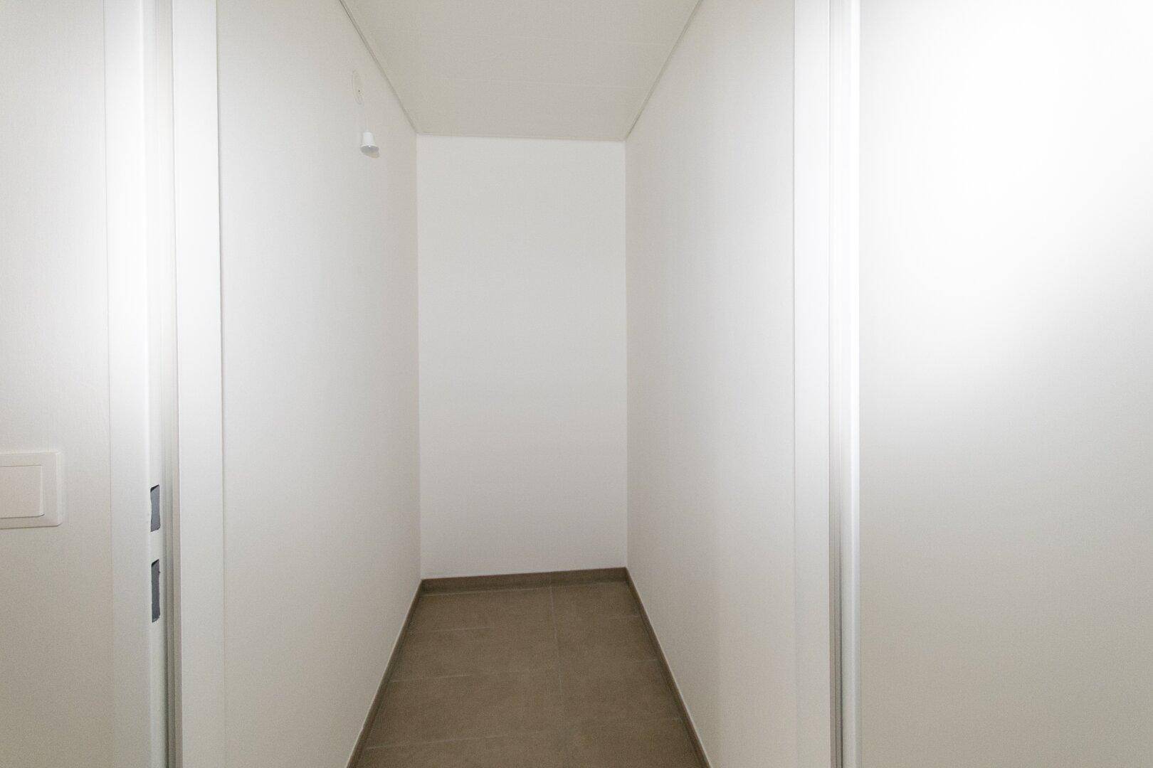 Kleiner, leerer Abstellraum mit Fliesenboden und weißen Wänden, ideal für Lagerzwecke.