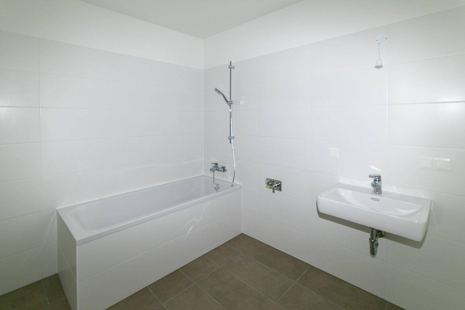 Modernes Badezimmer mit Badewanne, Waschbecken und weißen Wandfliesen.
