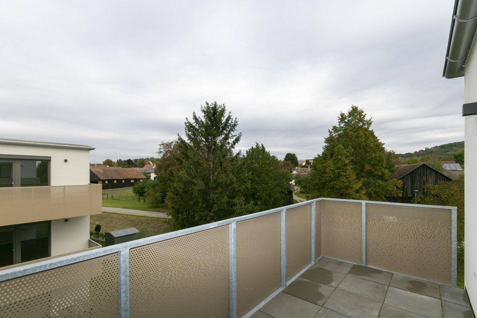 Geräumiger Balkon mit Blick auf die grüne Umgebung und weitere Gebäude der Wohnanlage.