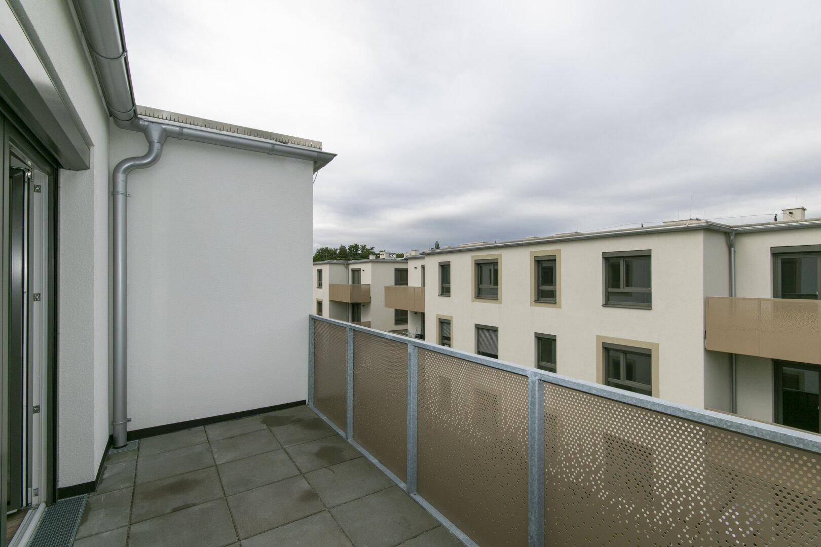 Balkon mit moderner Brüstung und Blick auf die benachbarten Wohngebäude der Siedlung.
