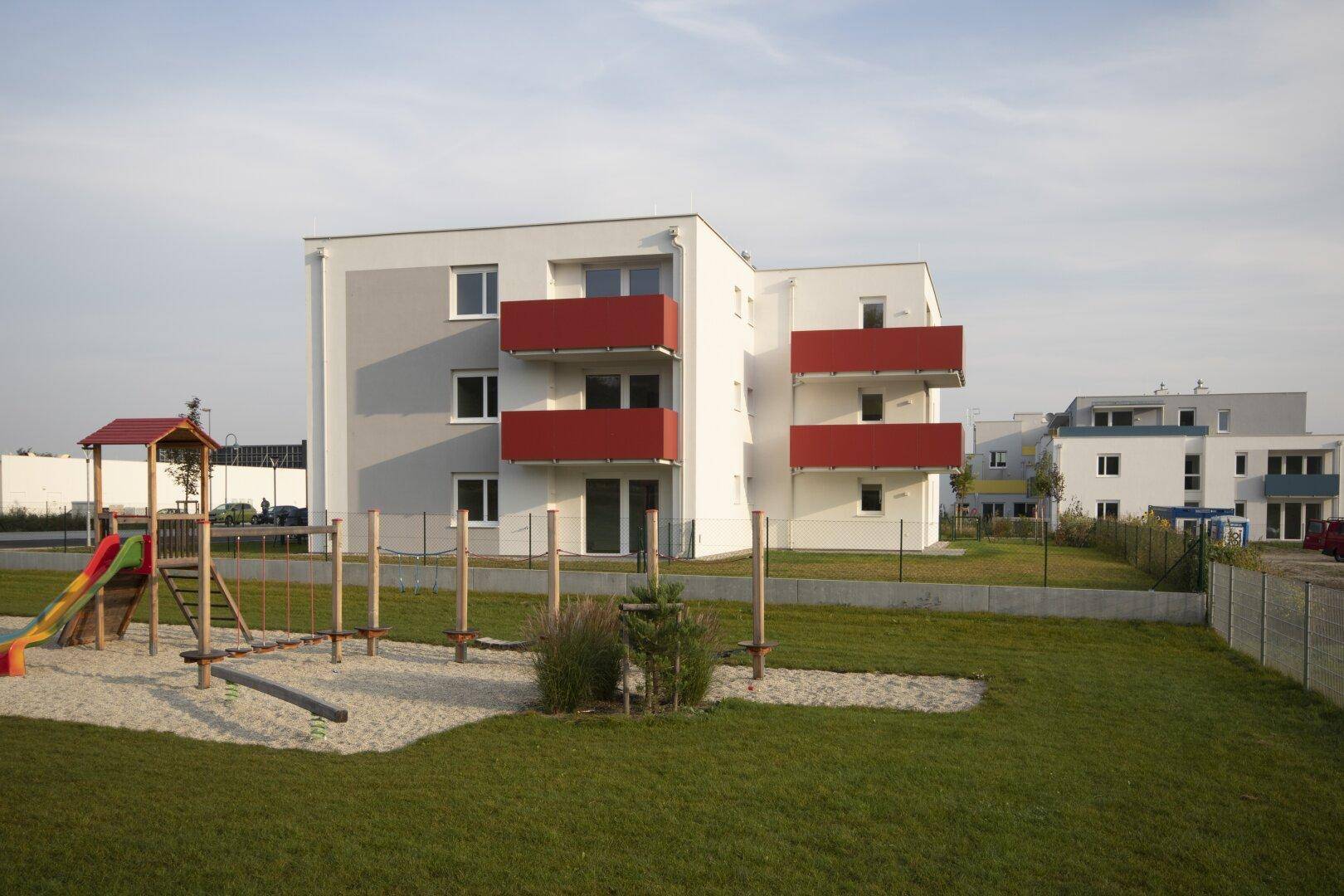 Modernes Wohngebäude mit Spielplatz und Grünflächen in der Umgebung.