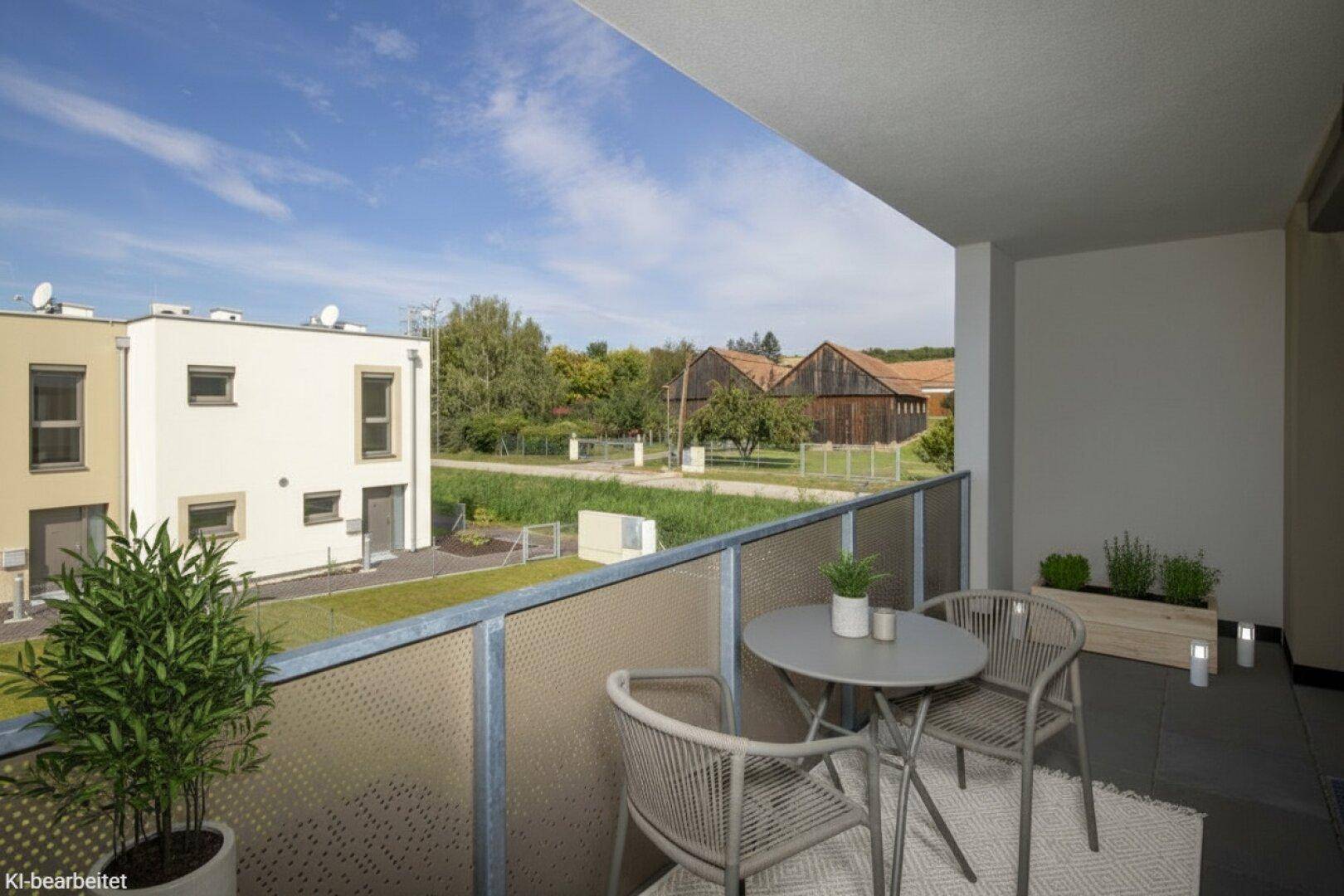 Gemütlicher Balkon mit Sitzgelegenheiten und Blick auf die umliegende Landschaft und Gebäude.