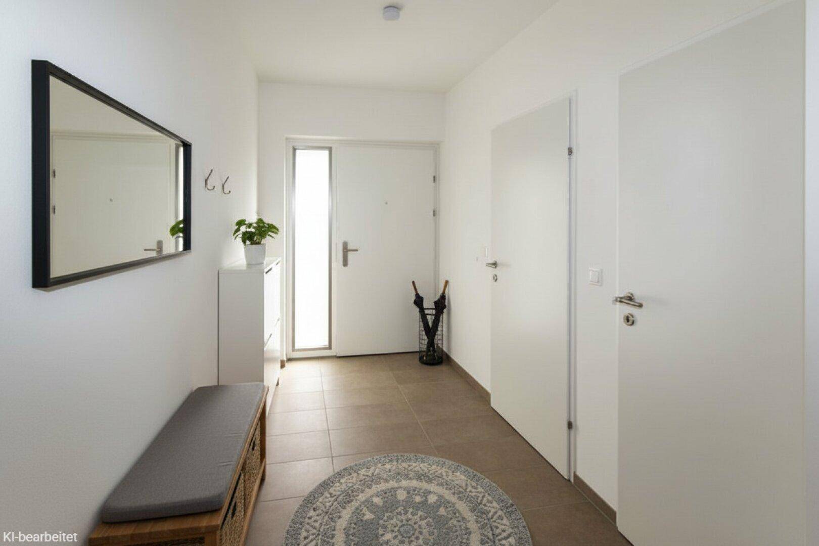 Heller Eingangsbereich mit Fliesenboden, Garderobe und einem großen Spiegel.