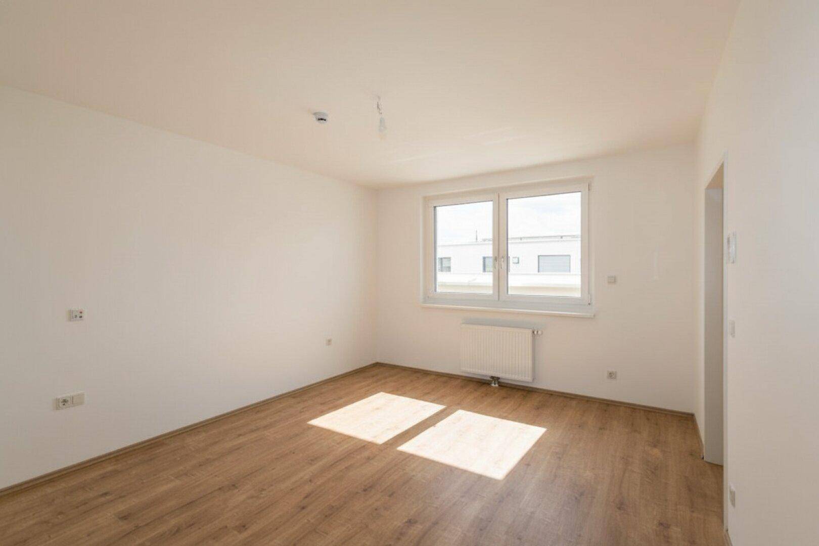 Helles Zimmer mit Laminatboden und großem Fenster, ideal als Schlaf- oder Arbeitszimmer nutzbar.