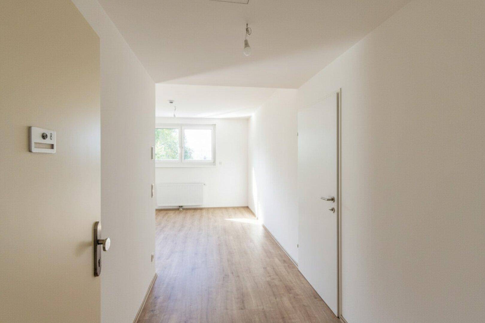 Heller Flur mit Laminatboden, der zu weiteren Räumen und einem Fenster führt.