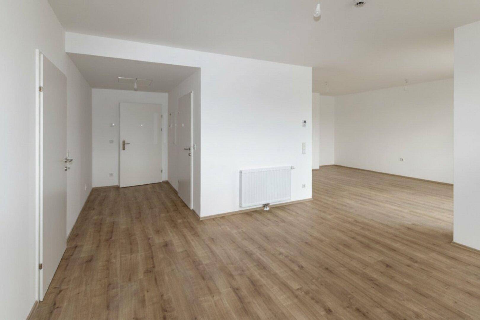 Heller Eingangsbereich mit Laminatboden und mehreren Türen, die zu verschiedenen Räumen führen.
