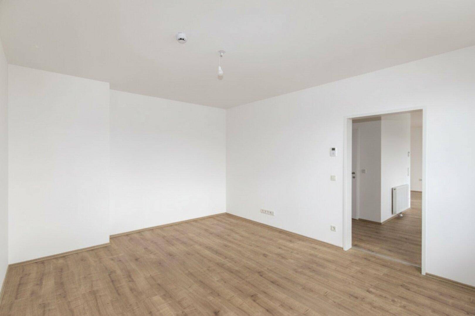 Geräumiger, heller Raum mit Laminatboden und weiß gestrichenen Wänden, ideal für individuelle Gestaltung.