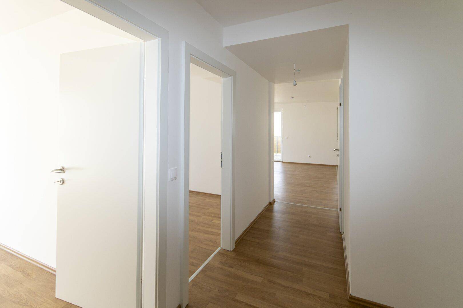 Langer, heller Flur mit Laminatboden, der die verschiedenen Wohnbereiche miteinander verbindet.