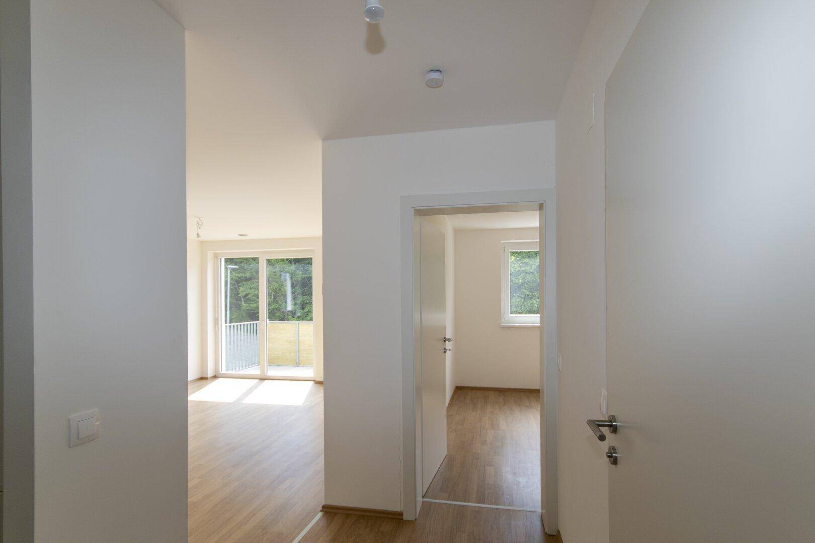 Flur mit Laminatboden und Blick in angrenzende, lichtdurchflutete Zimmer.