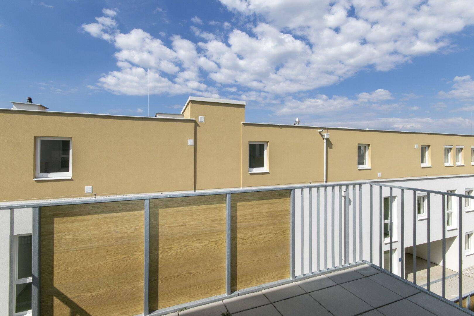 Sonniger Balkon mit moderner Holzverkleidung und Blick auf die Nachbarschaft.