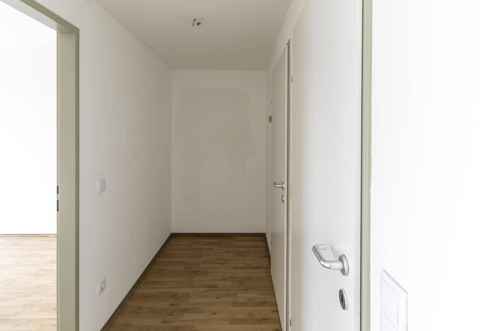 Langer, heller Flur mit mehreren Türen und durchgehendem Laminatboden.