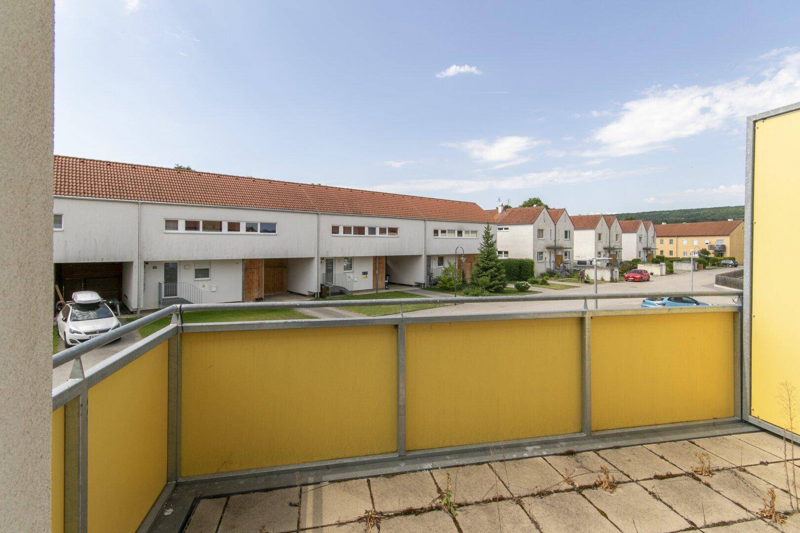 Balkon mit Ausblick auf die ruhige Wohnstraße und die benachbarten Reihenhäuser.