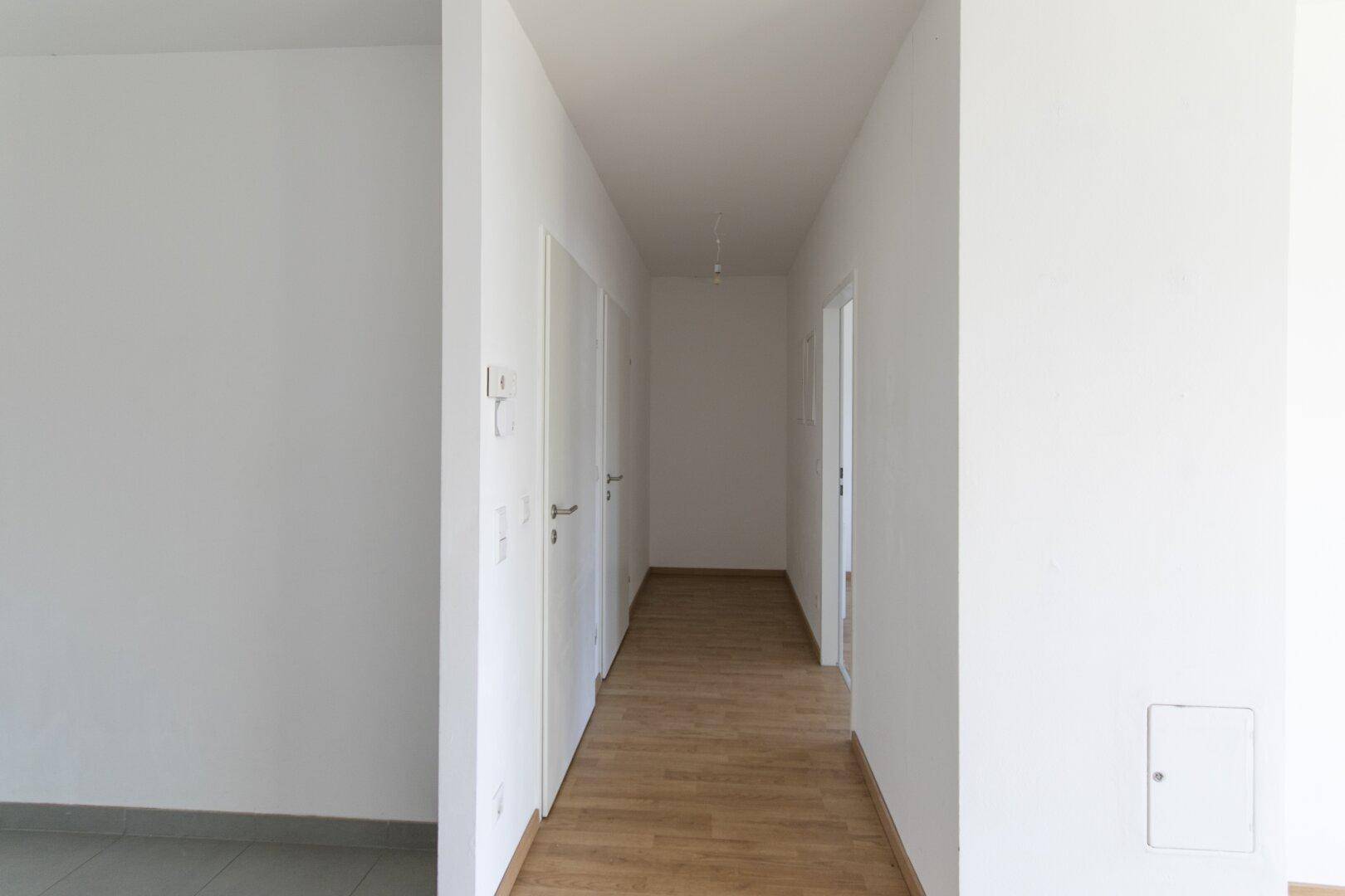 Langer, heller Flur mit Laminatboden und mehreren Türen zu den angrenzenden Räumen.