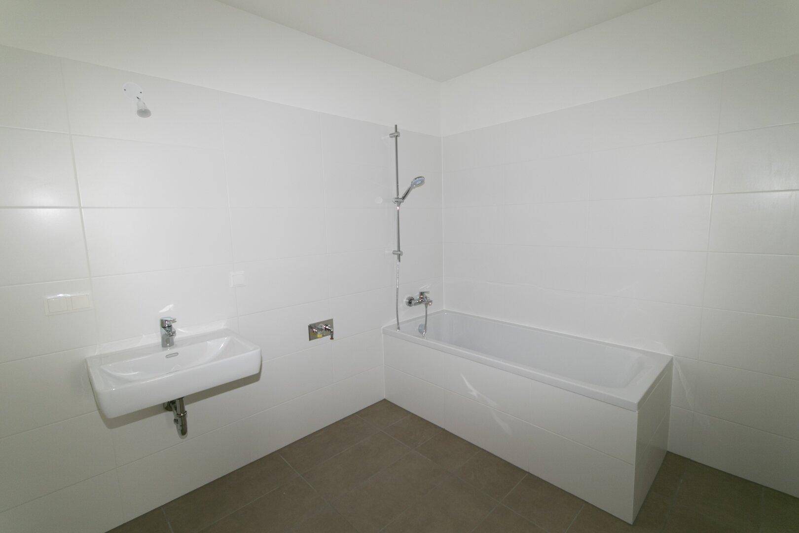 Modernes Badezimmer mit weißen Fliesen, Badewanne und einem einzelnen Waschbecken.