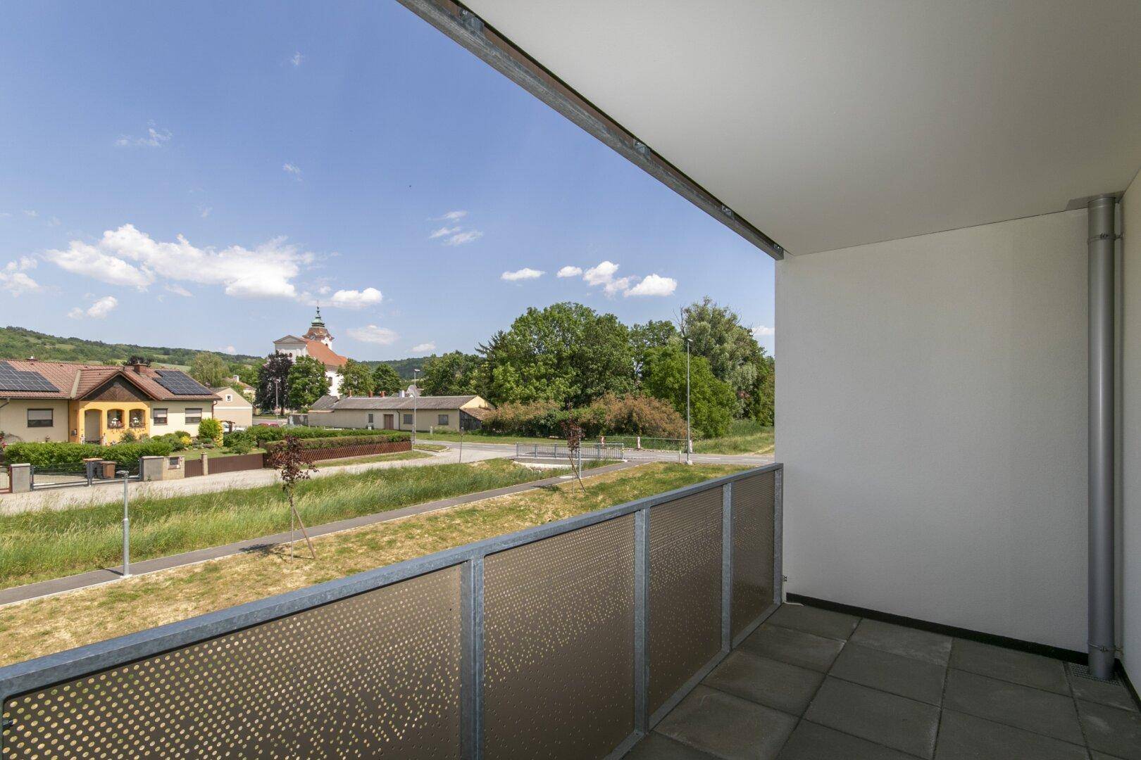 Heller Balkon mit weitem Blick über die ländliche Siedlung und die umliegende Natur.