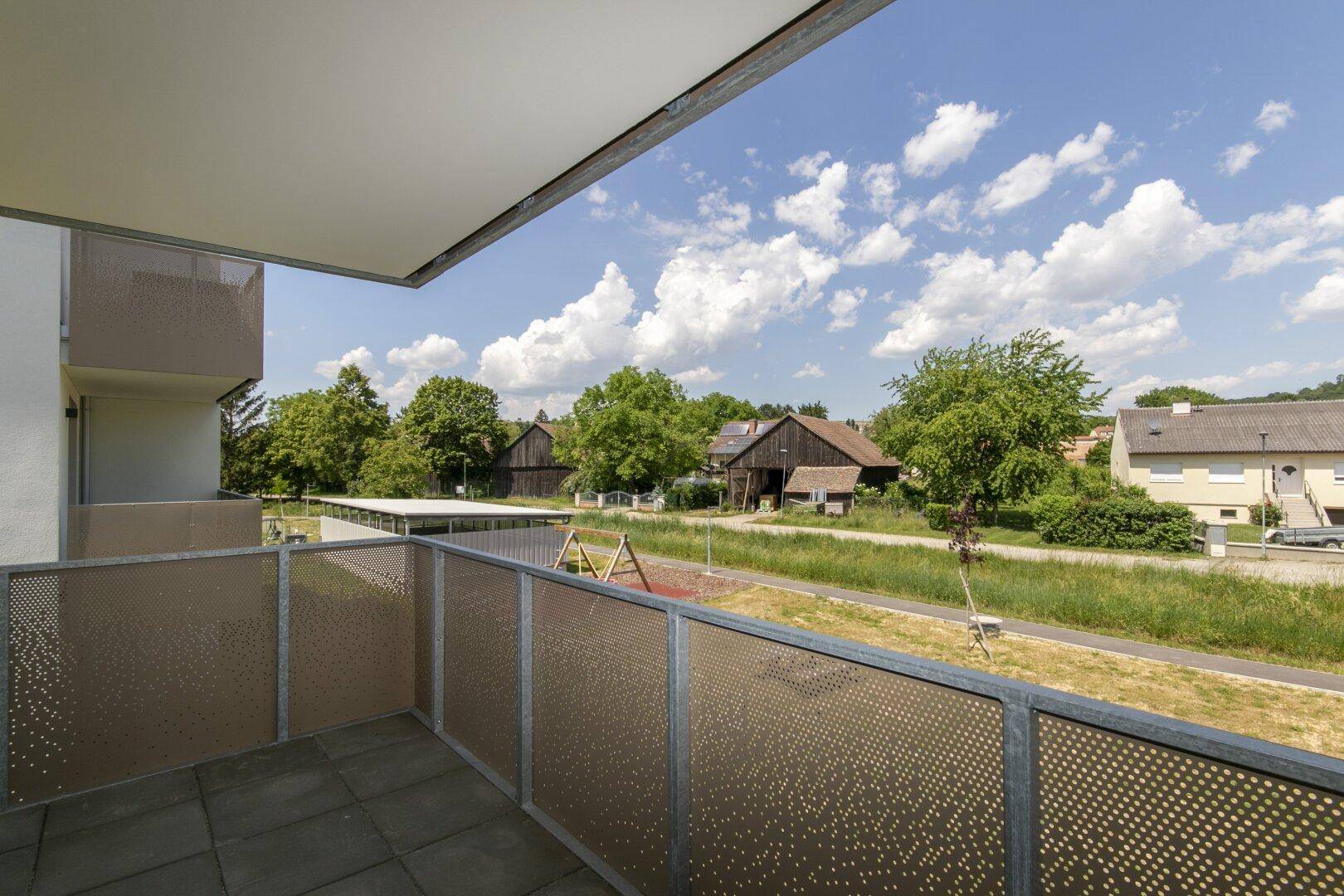 Geräumiger Balkon mit Blick auf die grüne Umgebung und einen kleinen Spielplatz.