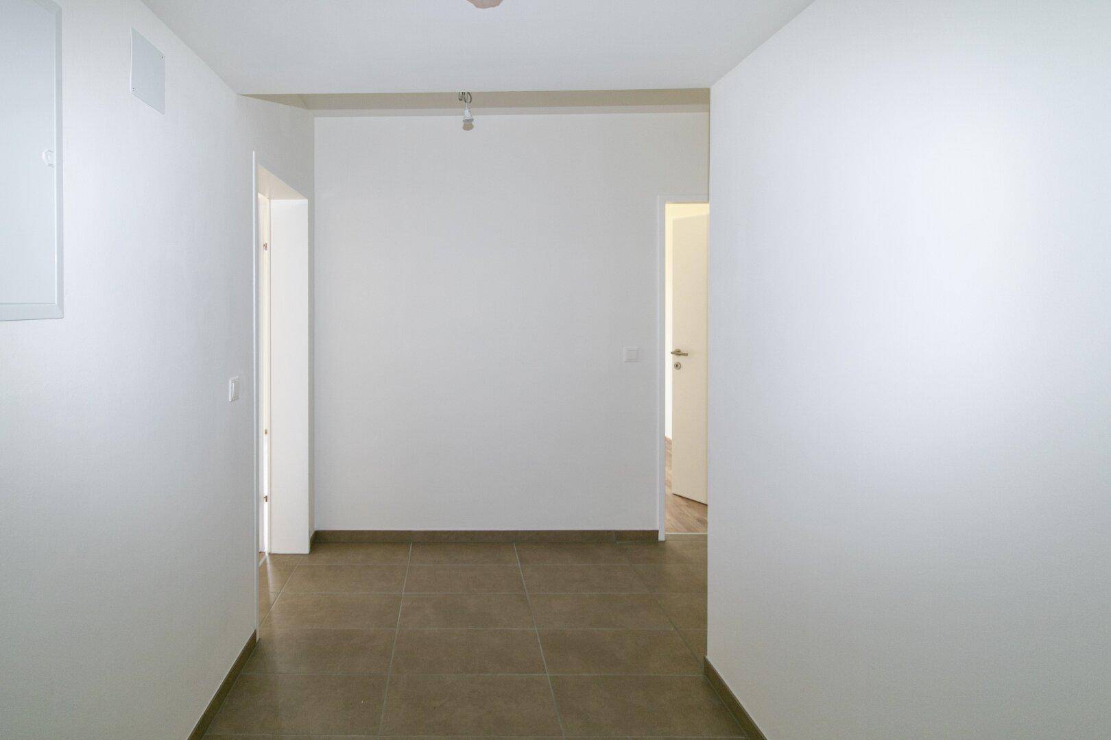 Geräumiger Flur mit Fliesenboden und weißen Wänden, der verschiedene Zimmer verbindet.