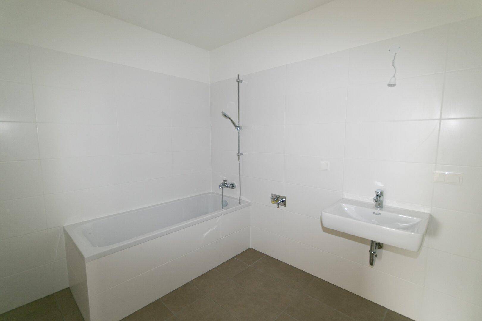 Helles Badezimmer mit Badewanne, Duschfunktion und einem modernen Waschbecken.