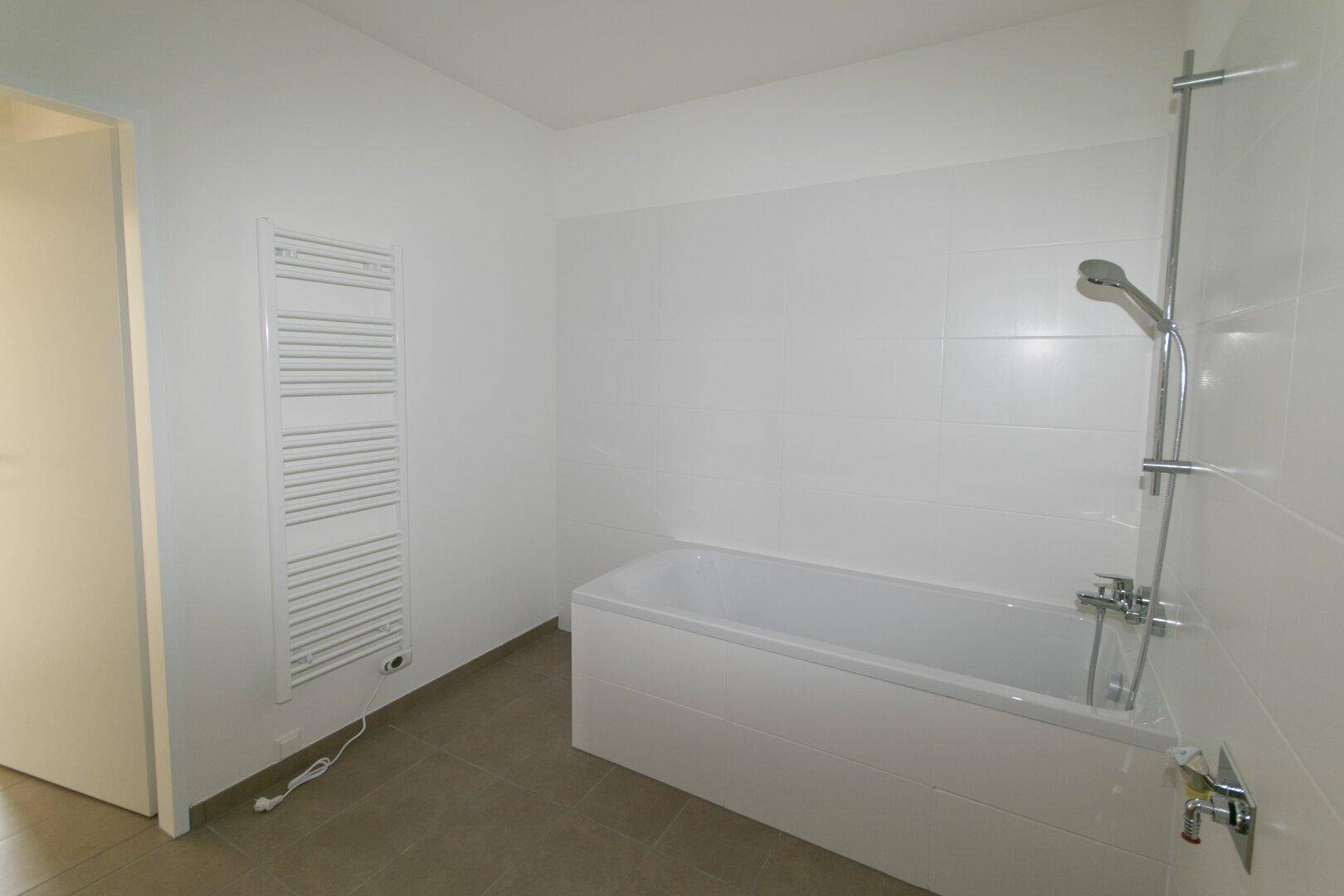 Modernes Badezimmer mit Badewanne, Duschfunktion und praktischem Handtuchheizkörper.
