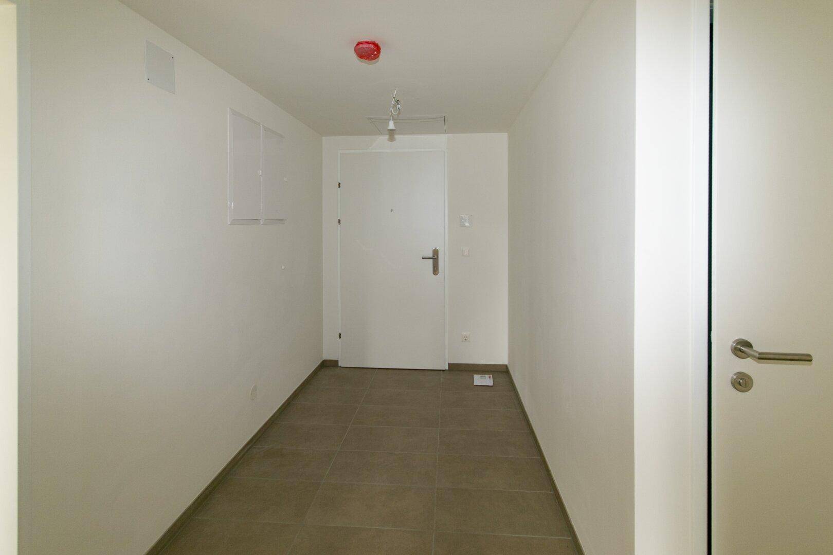 Heller Eingangsbereich mit Fliesenboden und weißer Eingangstür.