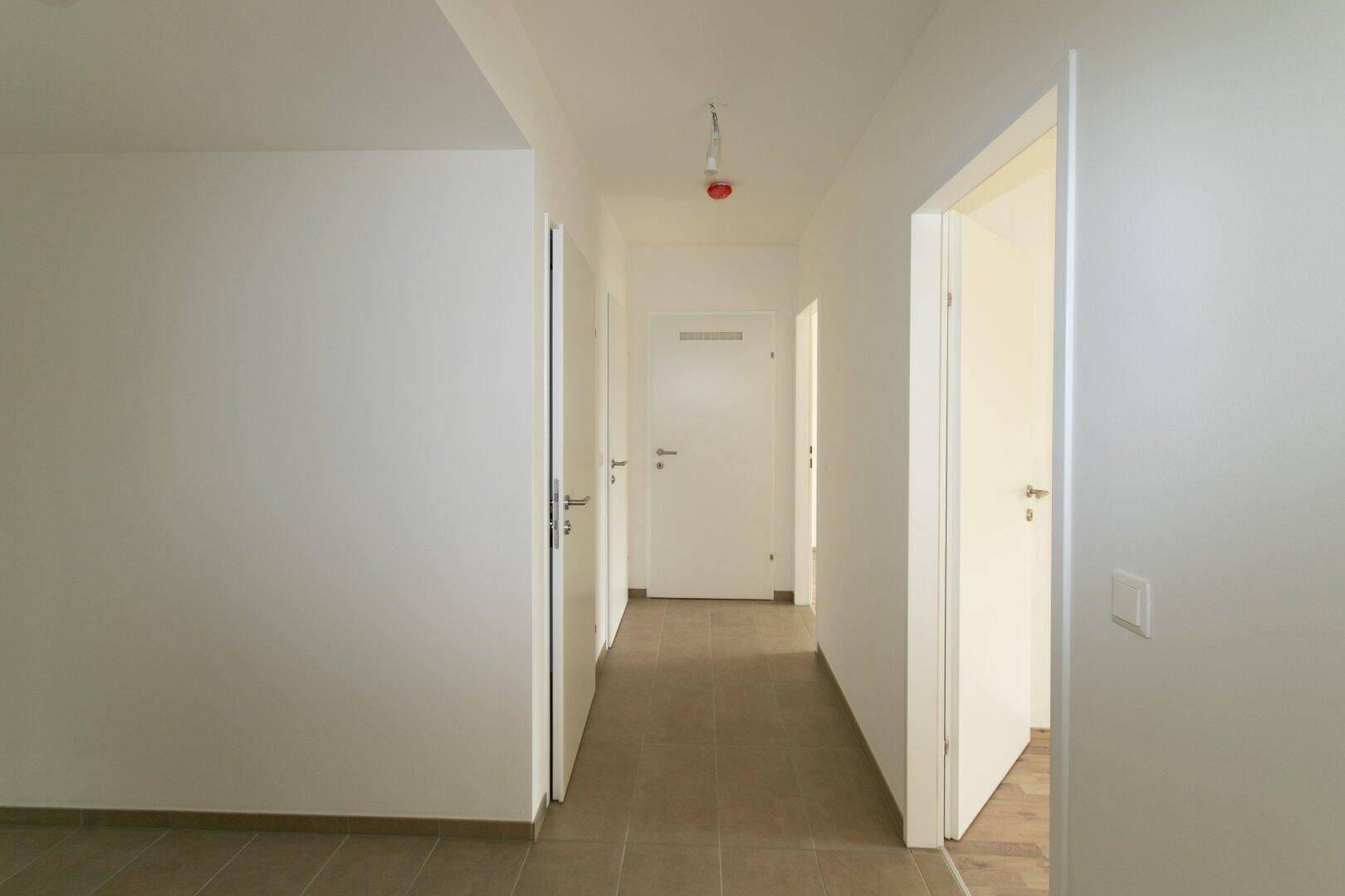 Langer, heller Flur mit Fliesenboden und mehreren Türen zu den angrenzenden Räumen.