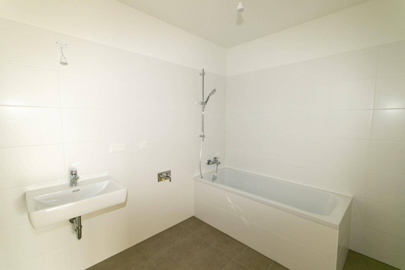 Modernes Badezimmer mit Badewanne, Waschbecken und weißen Wandfliesen.