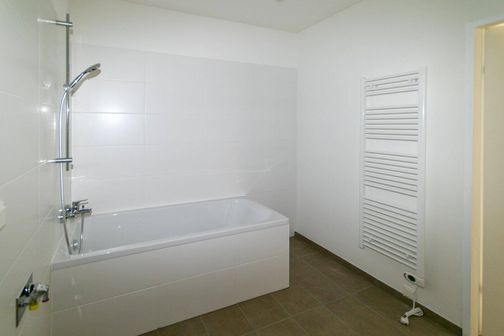 Helles Badezimmer mit Badewanne, Duscharmatur und beheiztem Handtuchhalter.