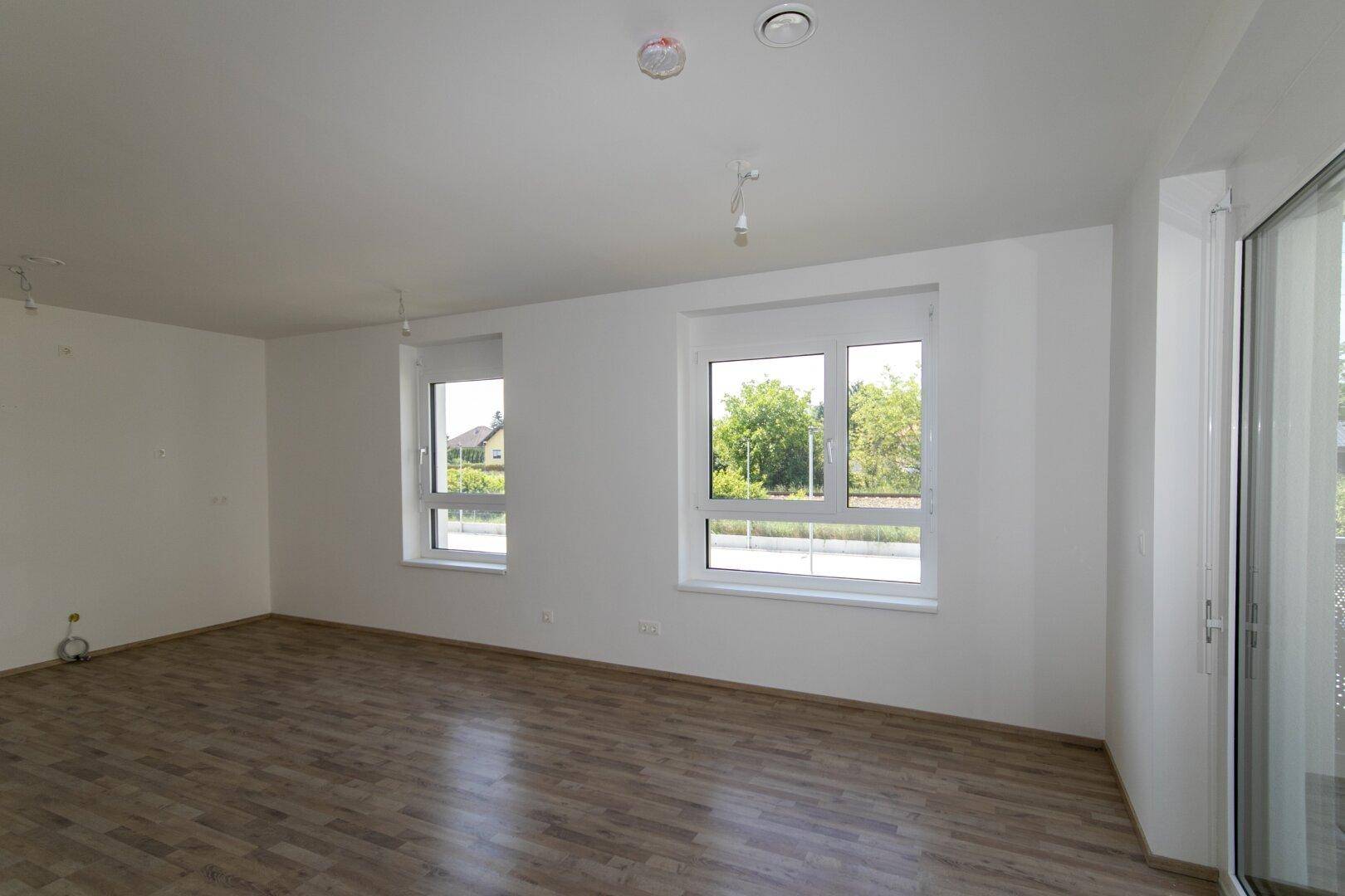 Heller Raum mit Laminatboden und Anschlüssen für eine zukünftige Küche.