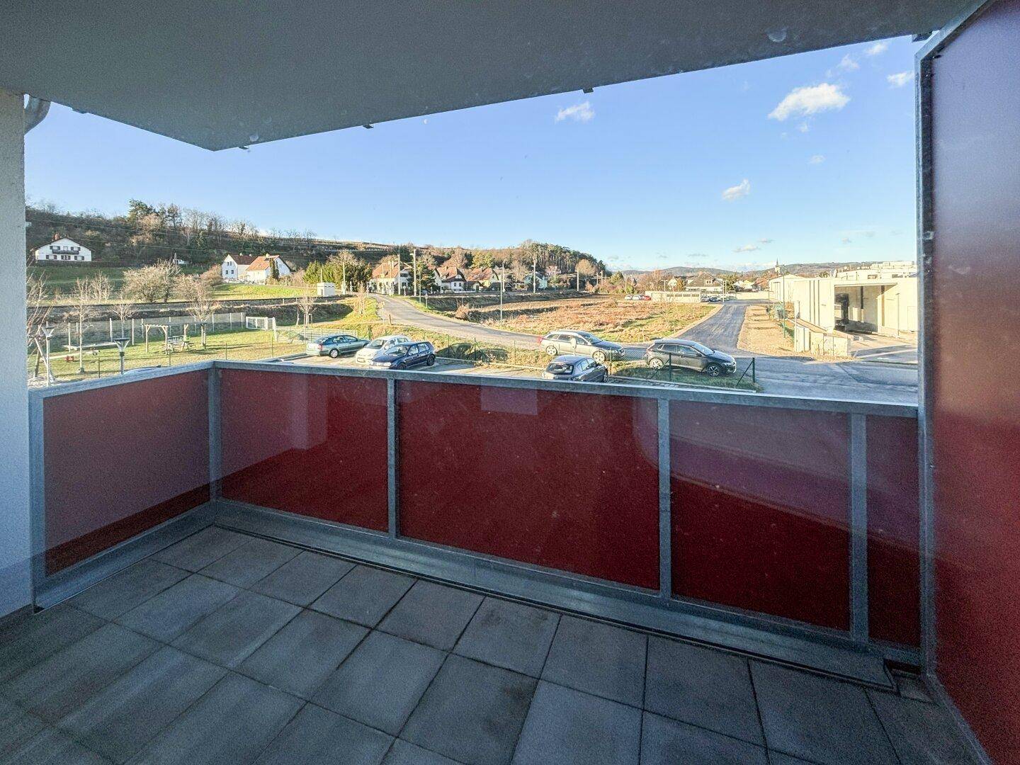 Balkon mit Fliesenboden und Blick auf die umliegende Landschaft und Straße.