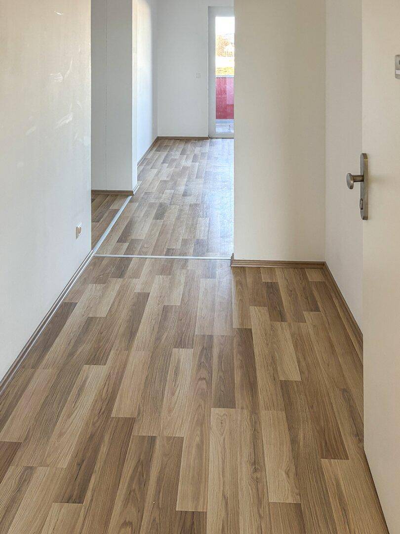Heller Flur mit Laminatboden, der zu weiteren Räumen führt.