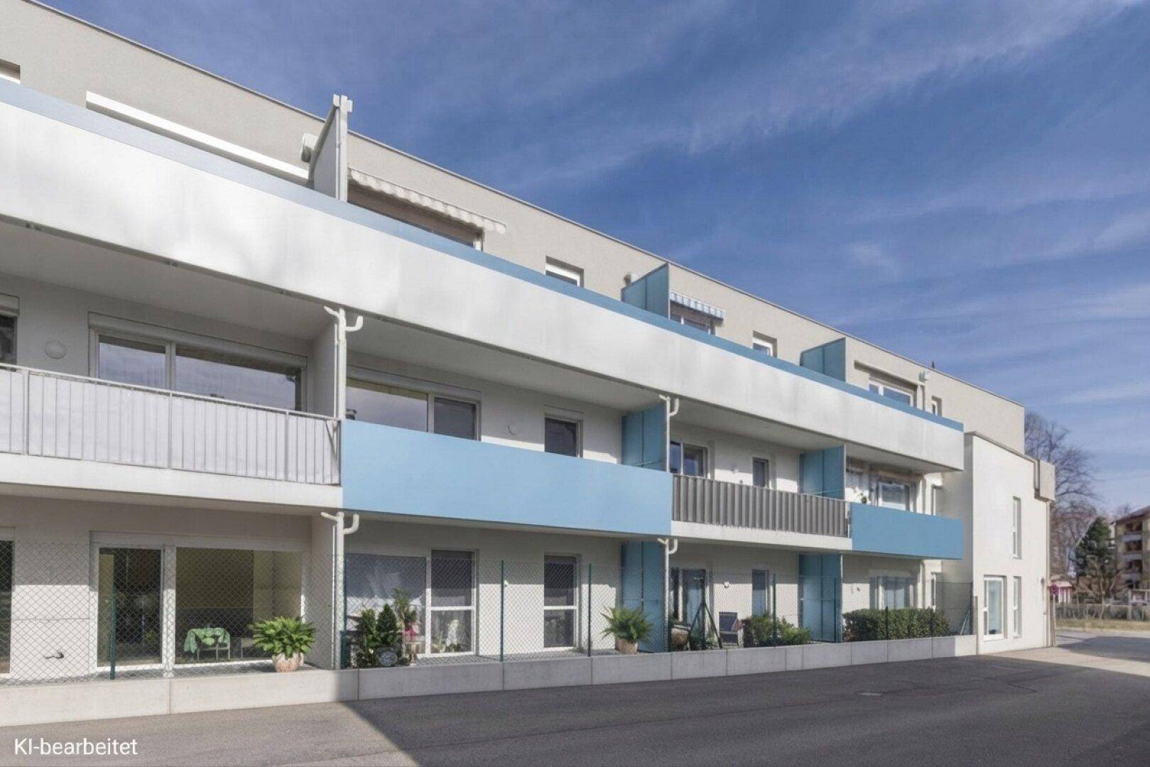 Lange Wohngebäudezeile mit blauen Akzenten an den Balkonen und großen Fensterfronten.