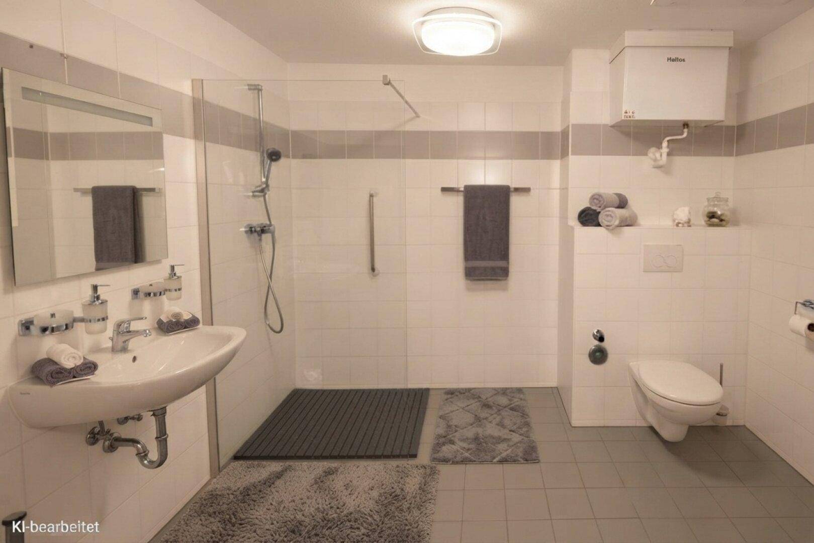Modernes Badezimmer mit ebenerdiger Dusche, Wand-WC und hellen Fliesen an Wänden und Boden.