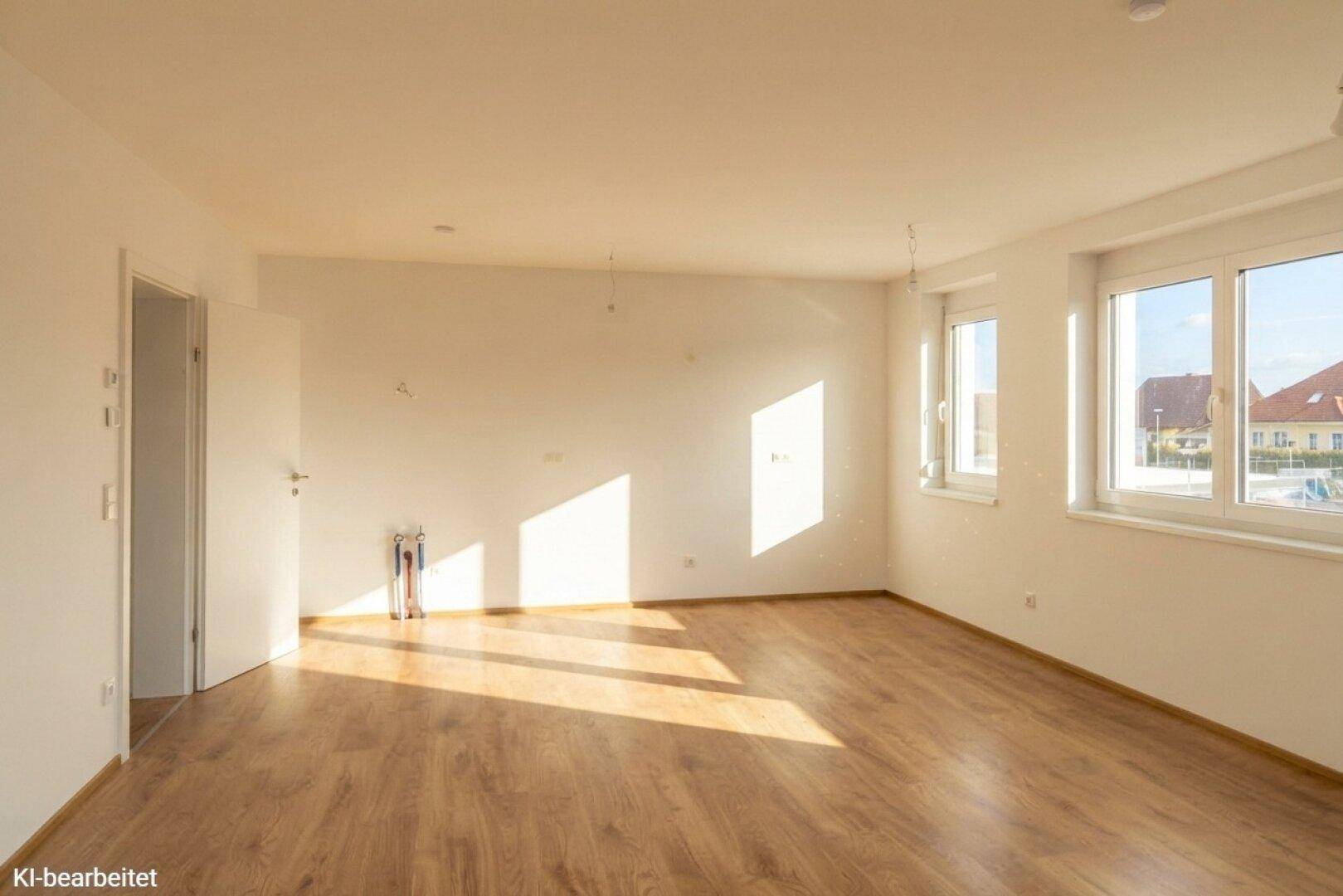 Geräumiger, heller Raum mit Laminatboden und Anschlüssen für eine Küche, ideal für offenes Wohnen.