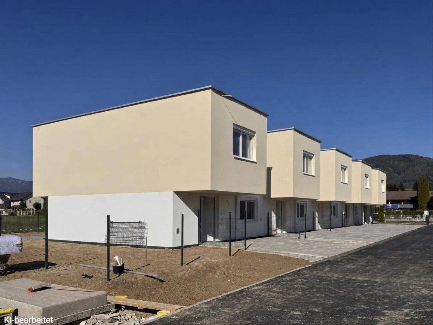 Reihe von modernen Neubauten mit beigefarbenen und weißen Fassaden unter klarem Himmel.