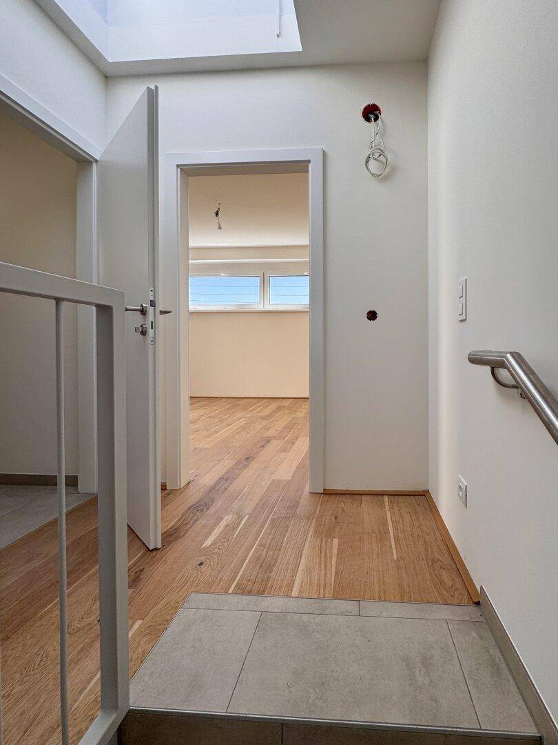 Heller Flur im Obergeschoss mit Holzboden, Oberlicht und Zugang zu weiteren Räumen.