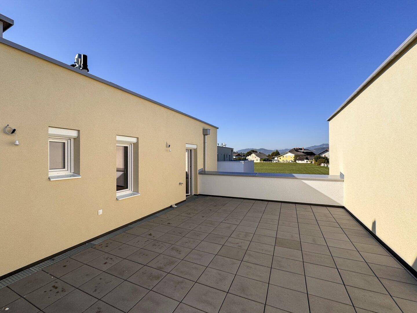 Weitläufige Dachterrasse mit Fliesen und Panoramablick auf die Landschaft und Berge.