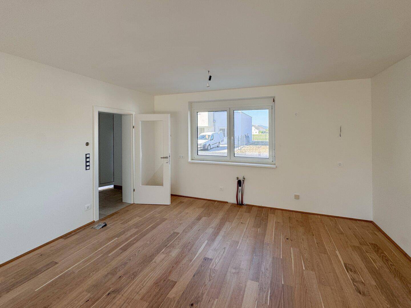 Geräumiger, heller Raum mit Holzboden und Fenster, vorbereitet für individuelle Nutzung.