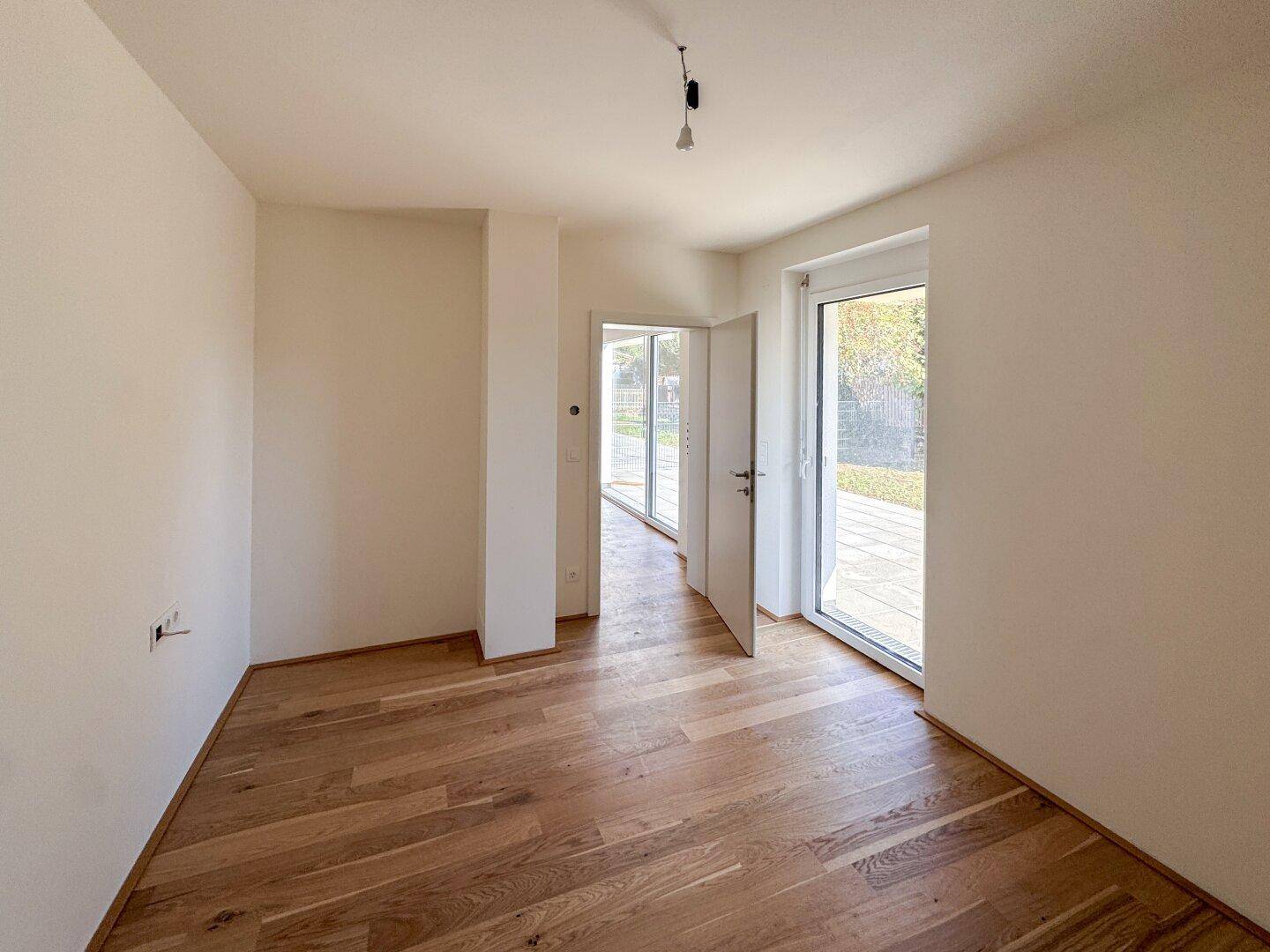 Heller Raum mit Holzboden und Zugang zu einem Außenbereich, ideal für Wohnzwecke.