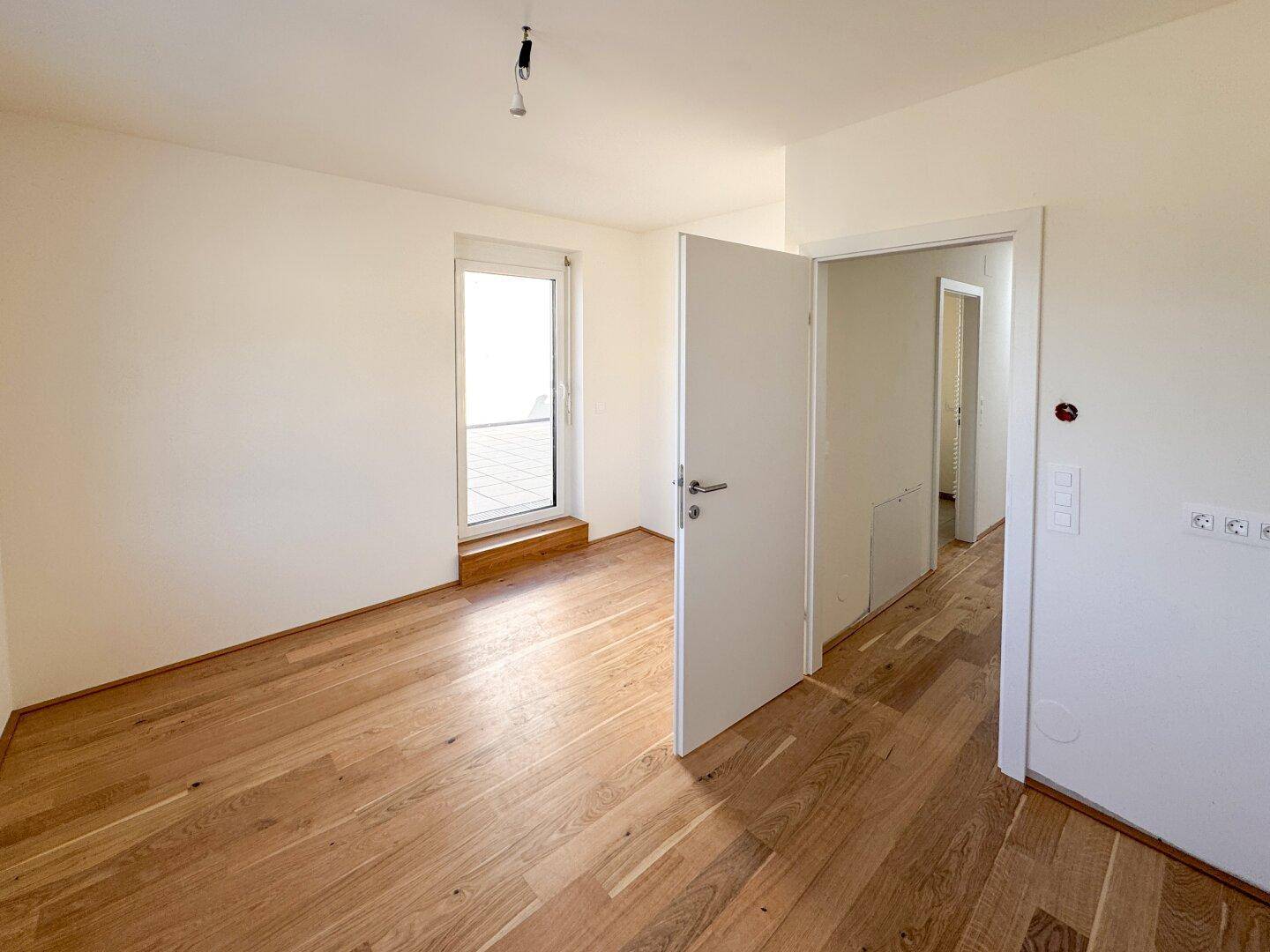 Helles Zimmer mit Holzboden und direktem Zugang zur Terrasse, ideal als Schlaf- oder Arbeitszimmer.
