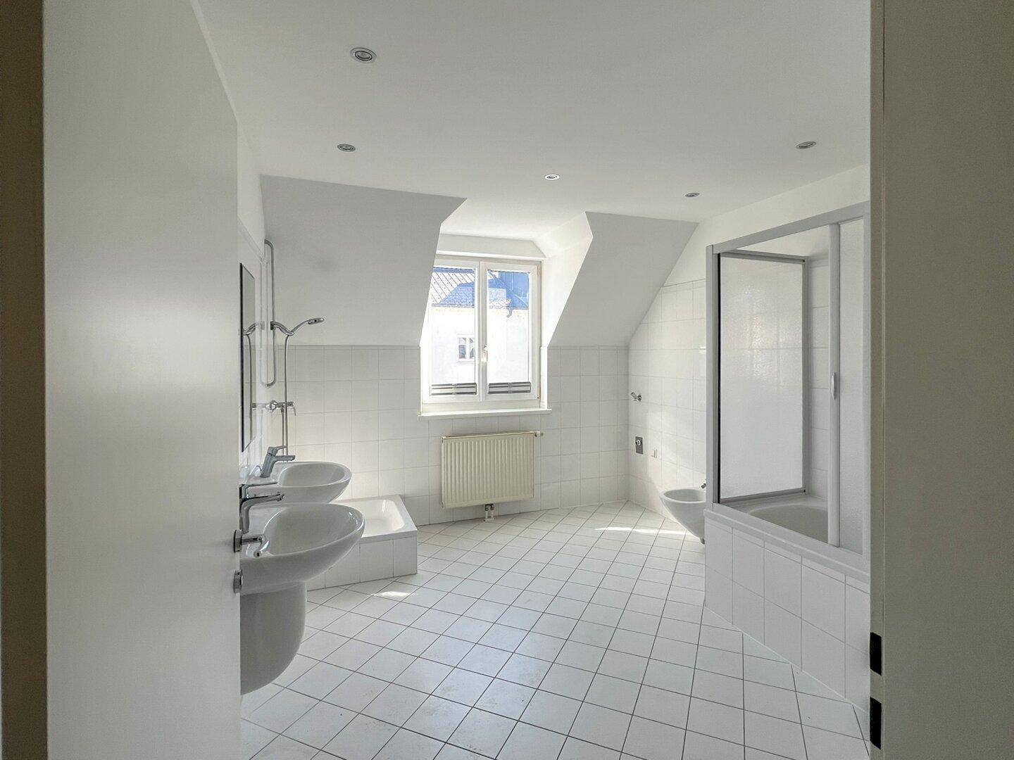 Helles Badezimmer im Dachgeschoss mit Doppelwaschbecken, Badewanne und separater Duschkabine.