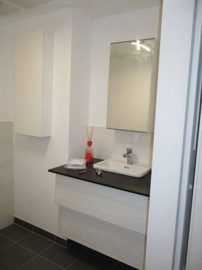 Gästetoilette mit modernem Waschbecken, Spiegelschrank und dunkler Ablagefläche für Komfort.